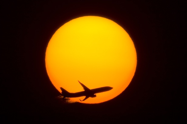 passenger jet flying by sun over Shanghai